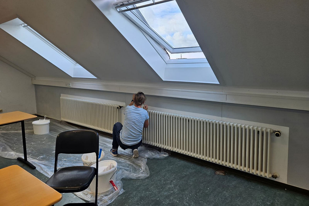 In einem Dachgeschossraum der Gesamtschule Schermbeck wird der Boden abgedeckt. Andrea Freitag arbeitet gerade an den Heizkörpern.