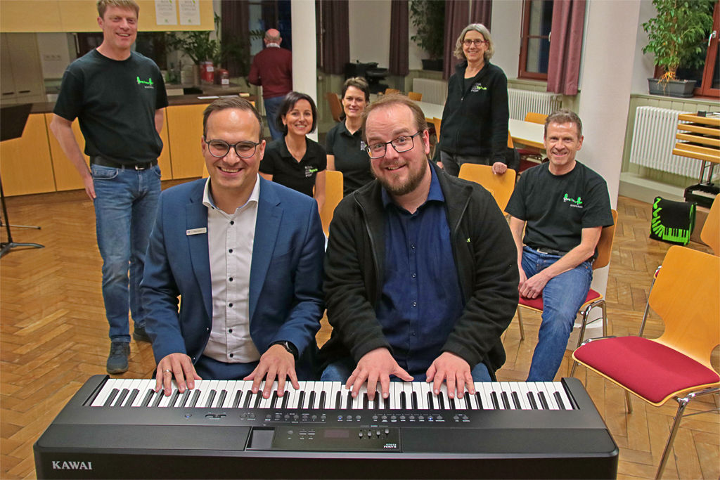 Mitglieder des Gesangverein Mundelsheim mit einem Bankmitarbeiter beim Spielen auf einem Keyboard