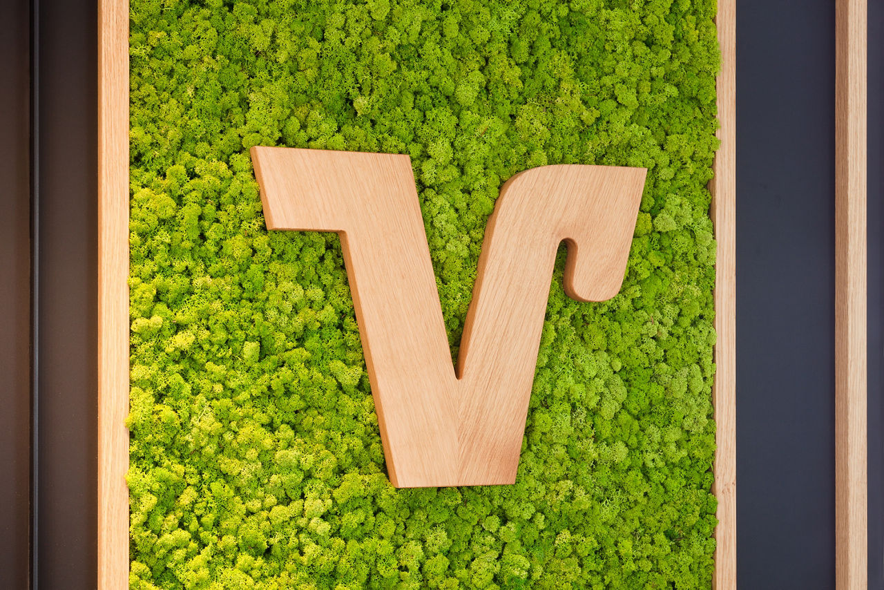 Volksbank V in Holz vor einer grünen Mosswand