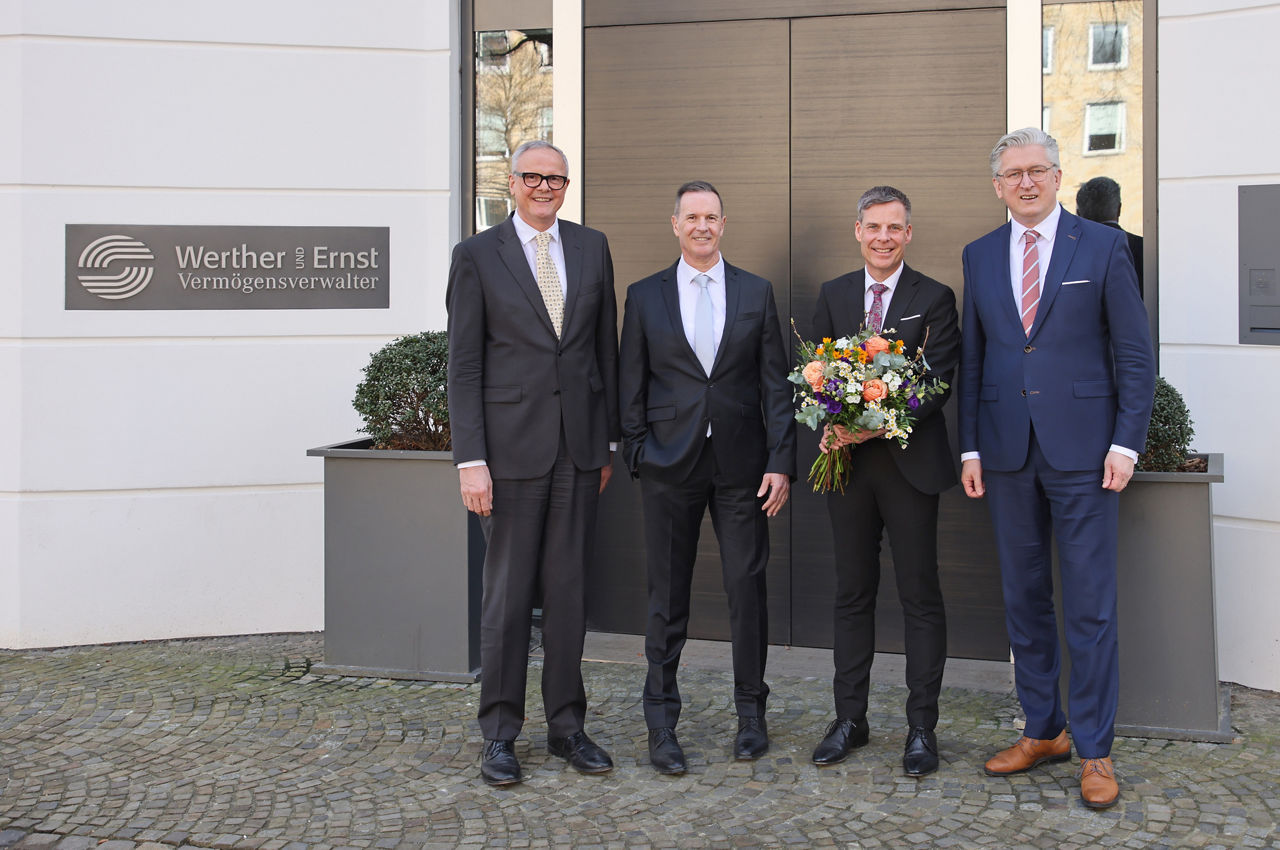 Die Geschäftsführung der Werther und Ernst Vermögensverwalter GmbH steht gemeinsam mit dem Vorstandsvorsitzenden der VerbundVolksbank OWL eG vor dem Unternehmen. 