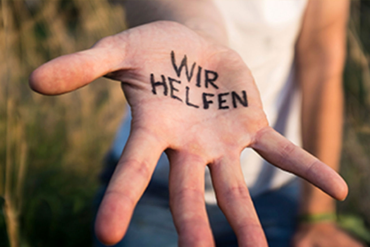 Mensch in der Natur mit der Aufschrift "Wir helfen" in der Handinnnefläche.