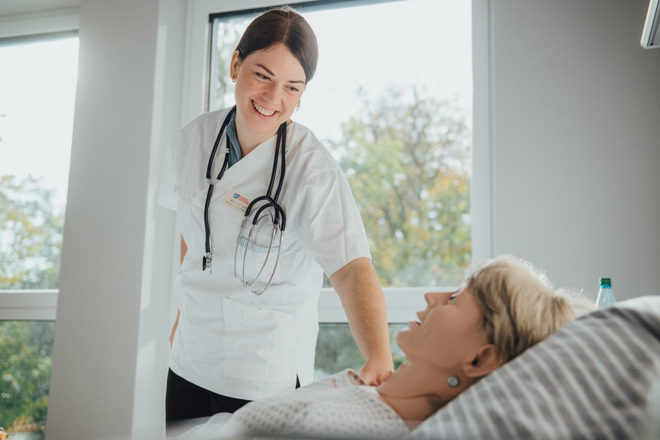 Eine Pflegerin simuliert eine Situation mit einer Patientenpuppe