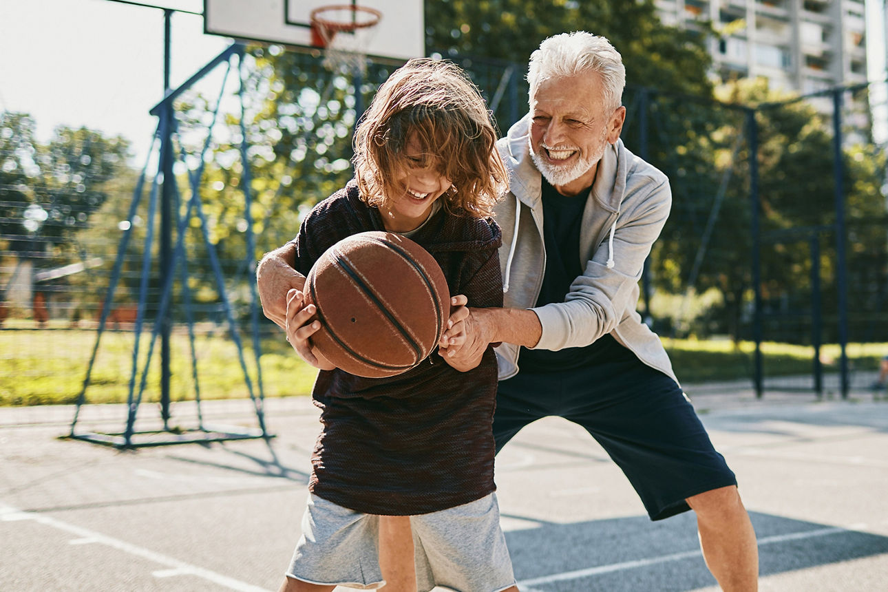 Älterer Mann spielt mit Jungen Basketball