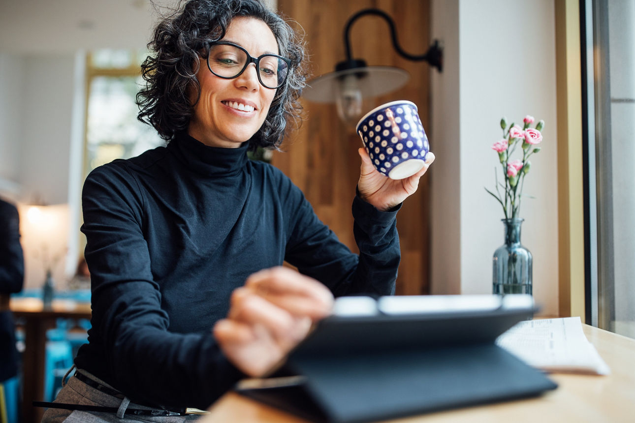 Frau lächelt in einem Cafe und bedient ihr Tbalet