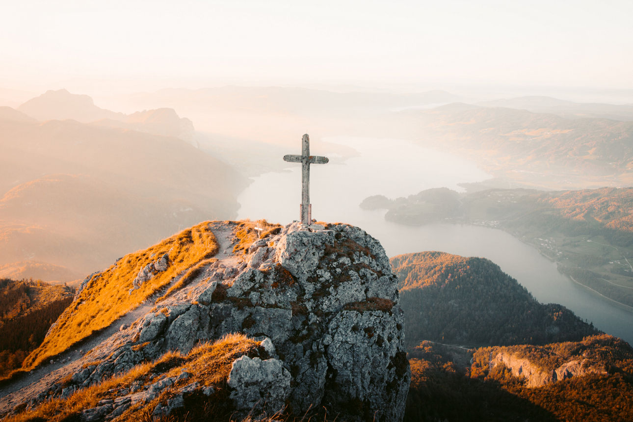 SEin Gipfelkreuz auf einem Berg in den Alpen im Sonnenuntergang