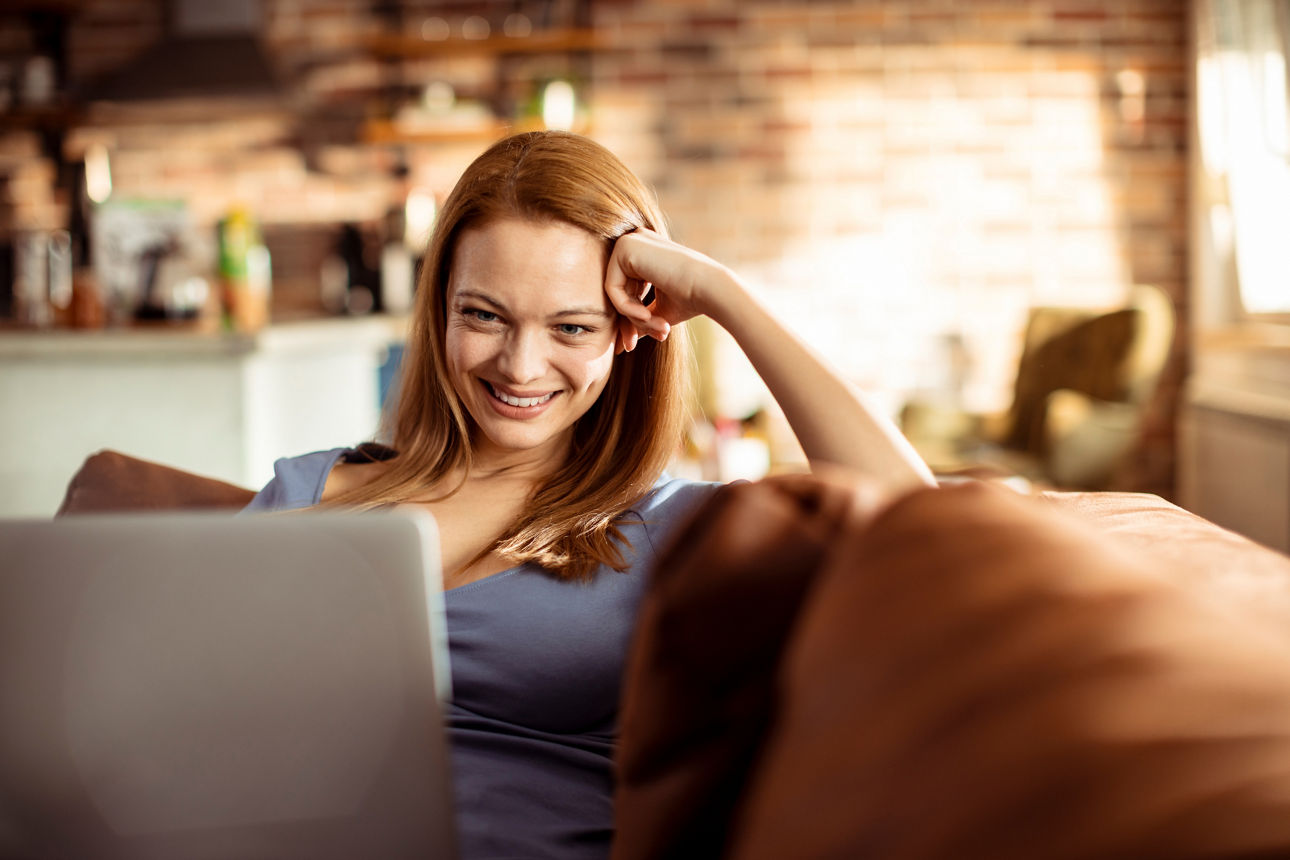 Eine Frau arbeitet am Laptop und lächelt