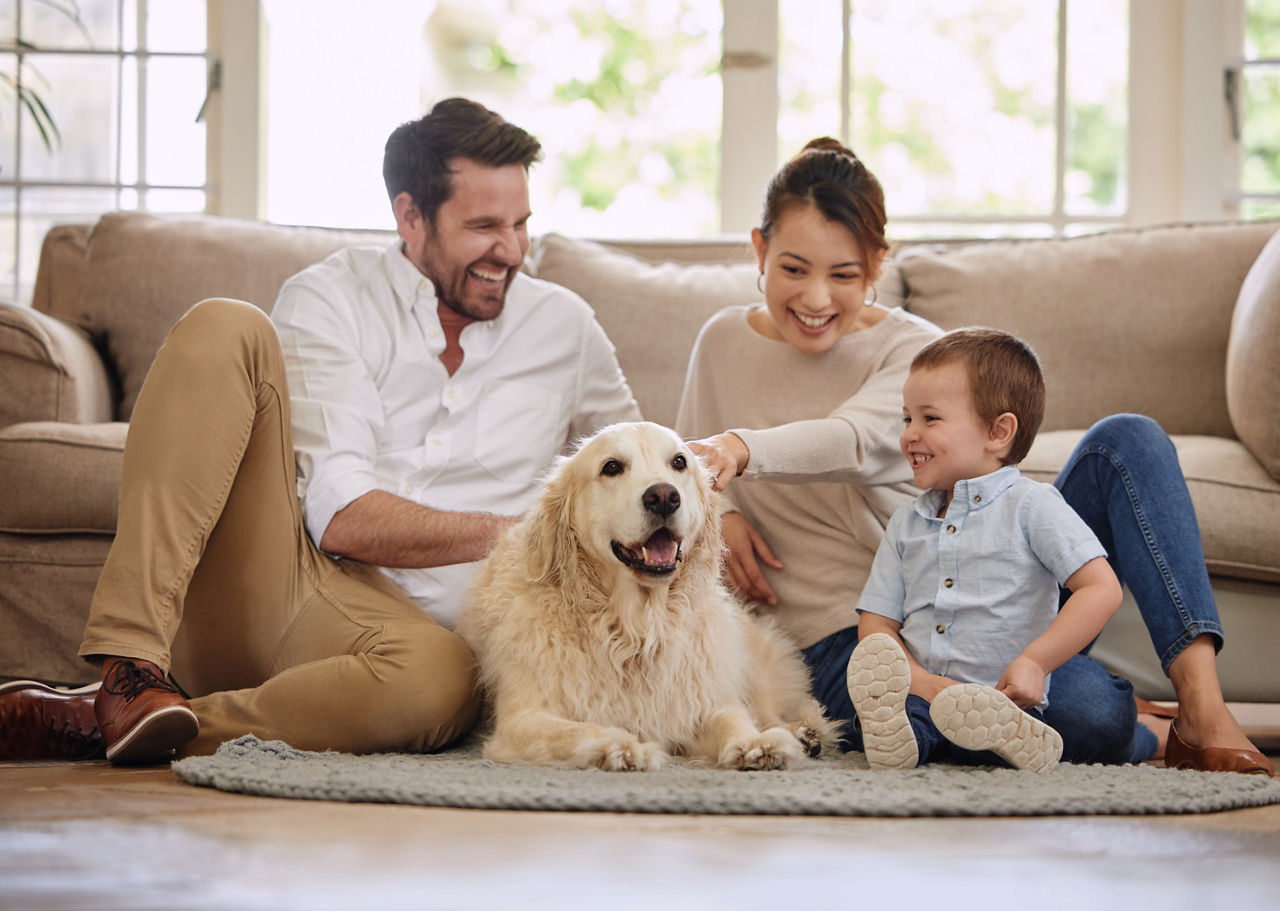 Aufnahme einer jungen Familie, die mit ihrem Hund auf dem Wohnzimmerboden sitzt