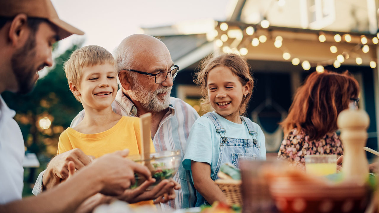Kinder sitzen mit den Großeltern an einem Tisch bei einem Fest