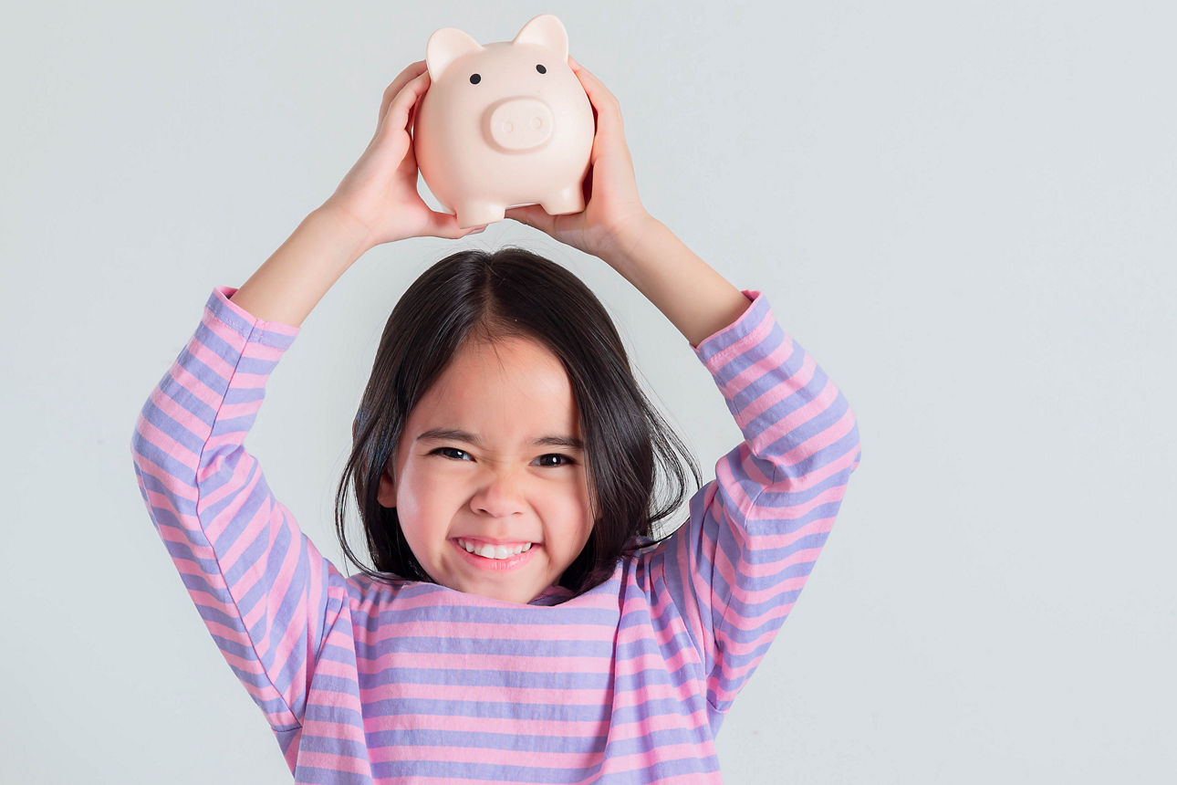 Kleines Mädchen spart Geld in einem Sparschwein