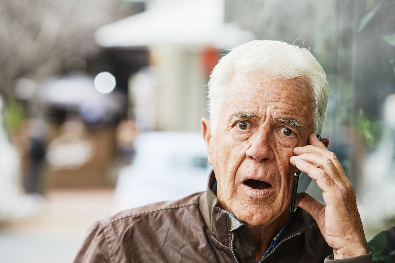 Ein älterer Herr mit erschrockenen Gesichtsausdruck hält sich ein Handy ans Ohr.