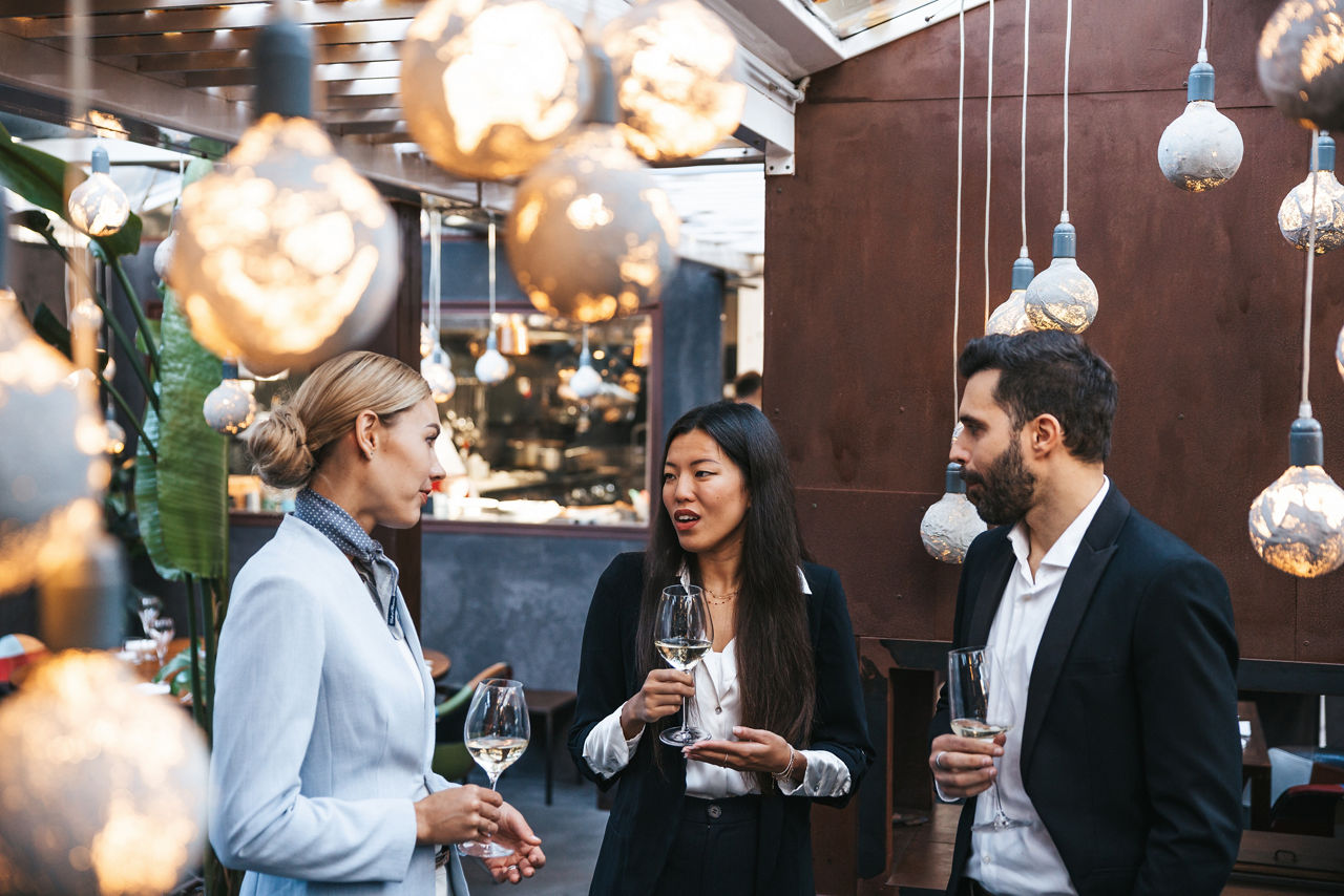 Geschäftsleute unterhalten sich während einer Veranstaltung in einem Luxusrestaurant. Sie trinken Wein und warte