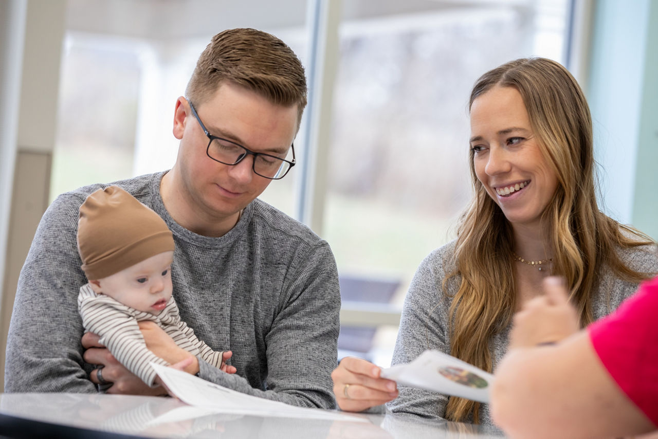 Eltern mit Baby im Gespräch mit ein weiteren Person