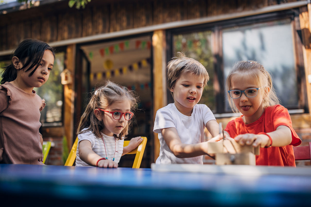 4 Kinder im Kindergartenalter basteln zusammen an einem Tisch