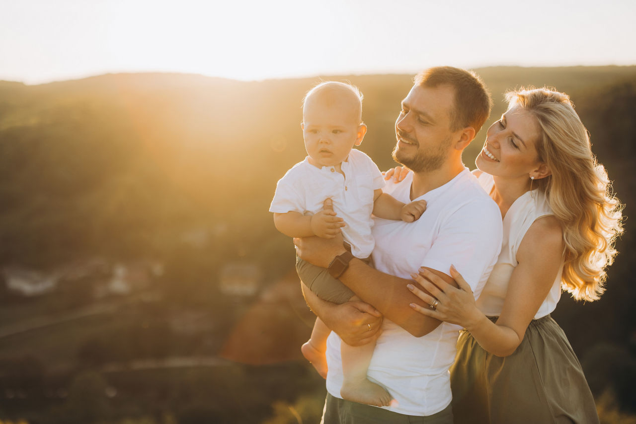 Eine fröhliche Familie steht auf einem Hügel und genießt das goldene Sonnenlicht.