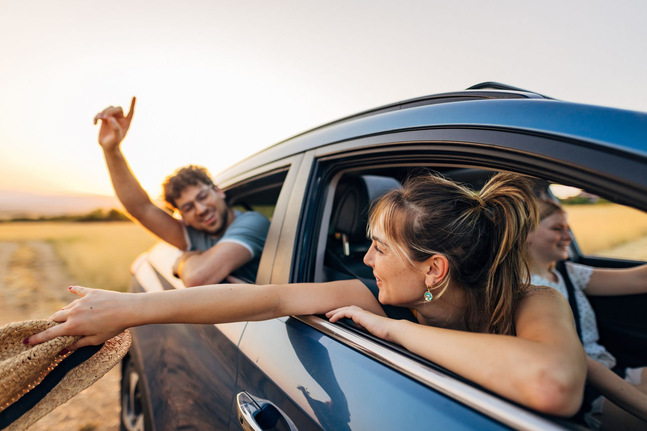 A small group of best friends enjoying a cheerful road trip to their summer vacation destination. They share joyful moments inside the car
