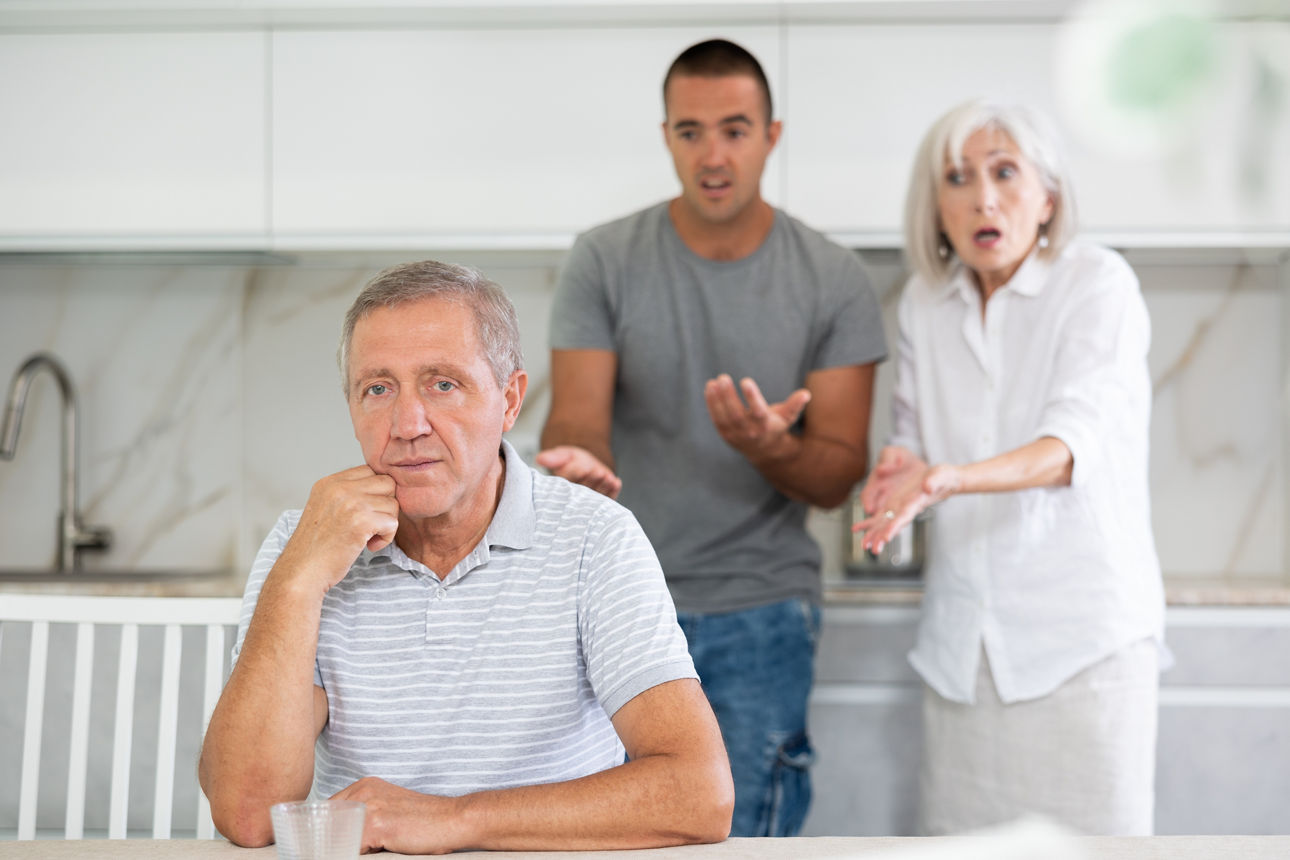 Adult man sits at table and thinks how to resolve conflict with his wife and son
