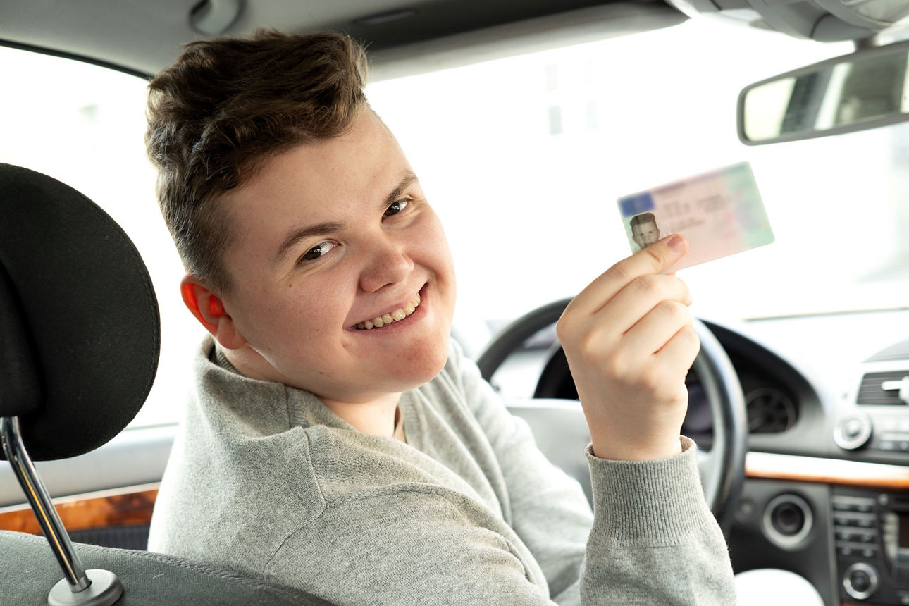 Junger Mann der seinen Führerschein zeigt nach bestandener Prüfung