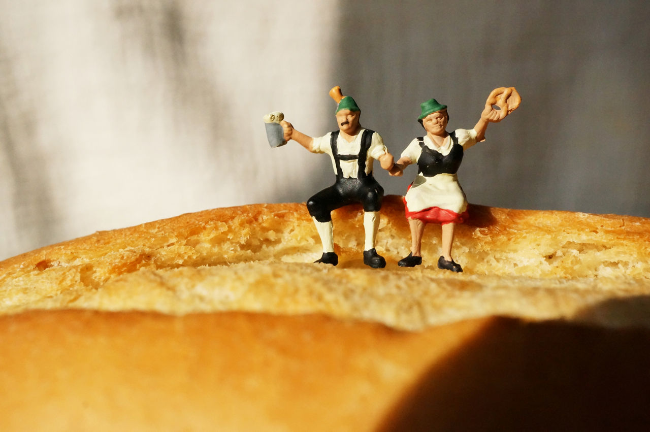 Miniaturfiguren in bayerischen Trachten sitzen auf einem Brötchen