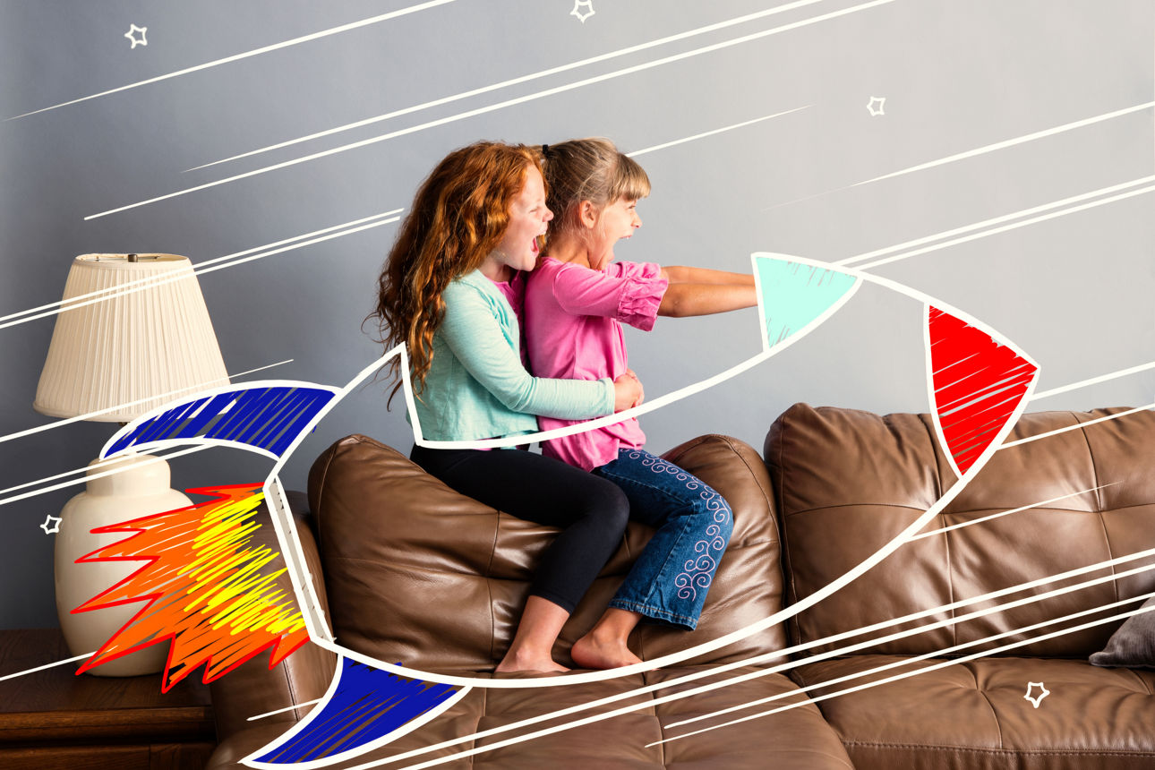 7 and 9 year old sisters sitting on a sofa pretending to be riding in a rocketship