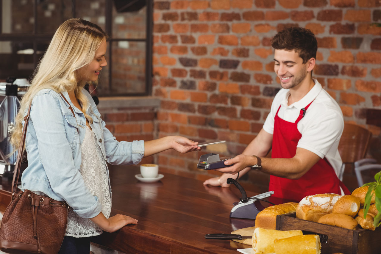 Pretty customer making a mobile payment at the coffee shop