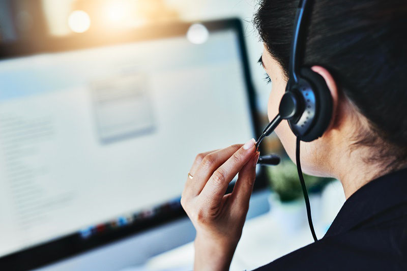  Rückansicht einer jungen Frau, die in einem Callcenter arbeitet