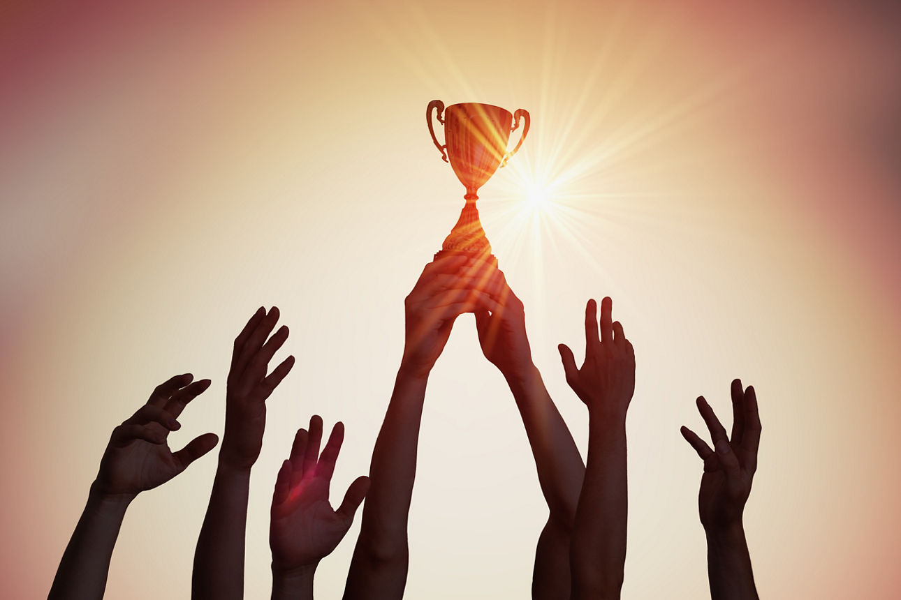 Hände halten einen Pokal in die Luft.