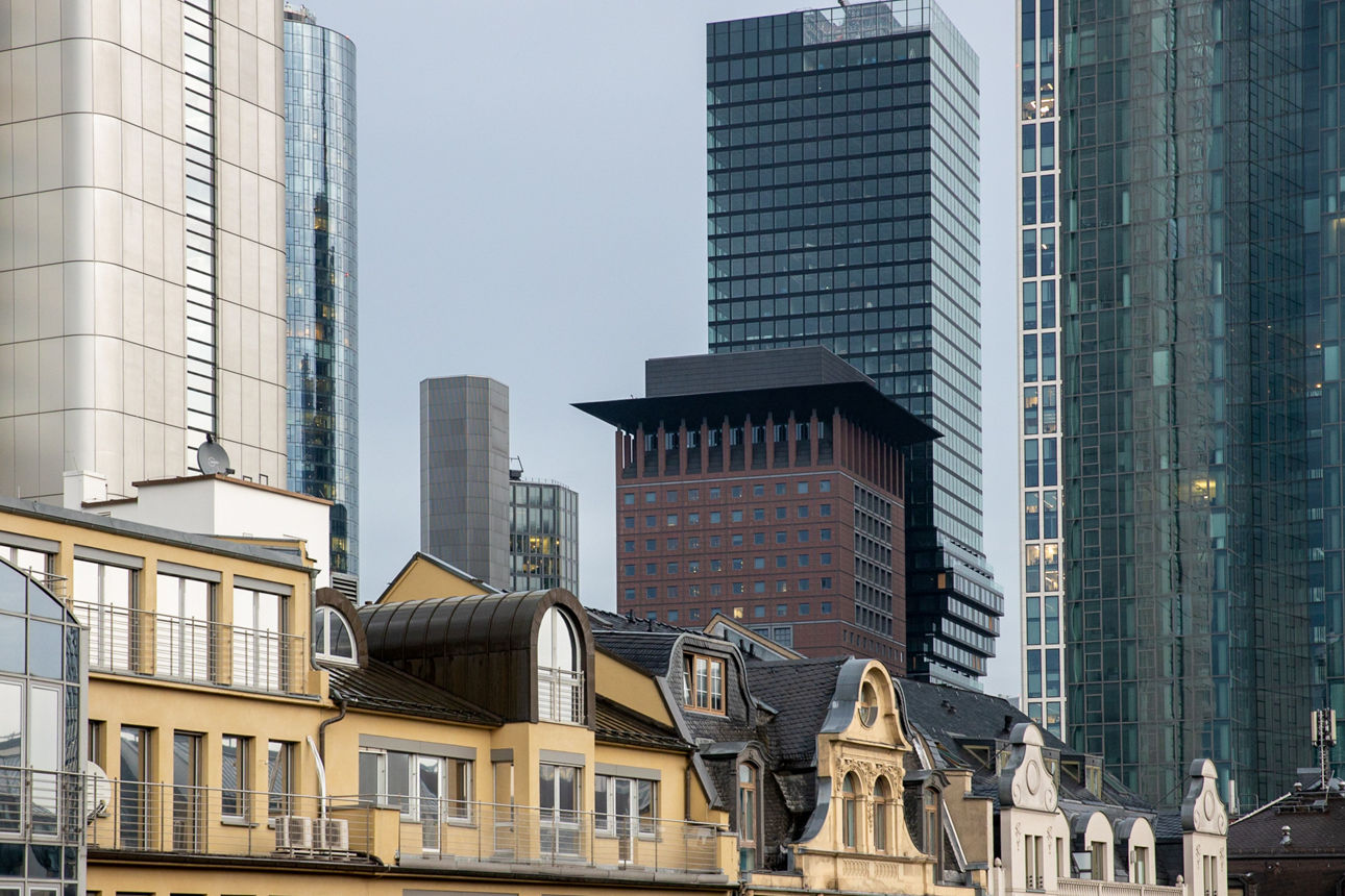 Kontrast zwischen historischer Architektur und modernen Wolkenkratzern in einem urbanen Geschäftsviertel bei bewölktem Himmel