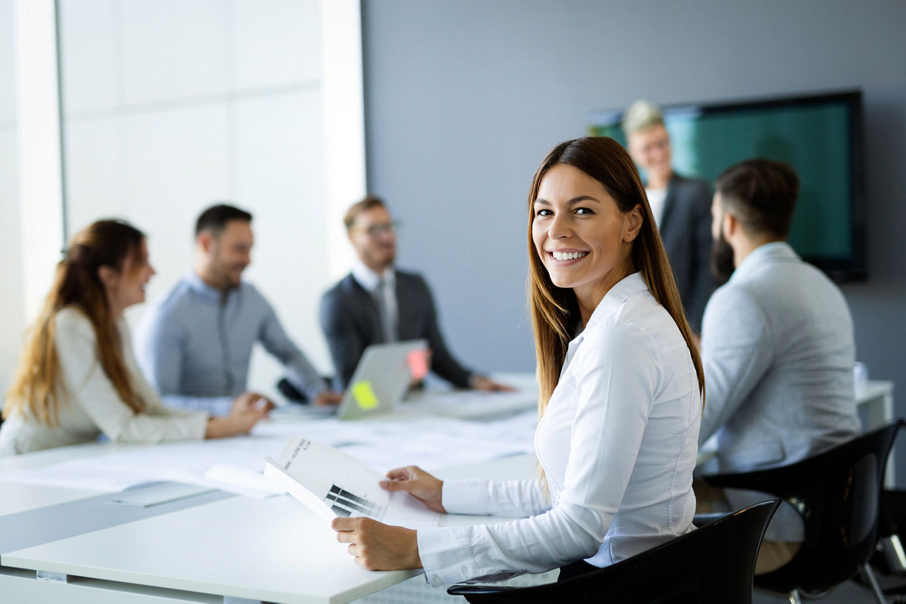 Junge Frau im Meeting schaut lächelnd in die Kamera