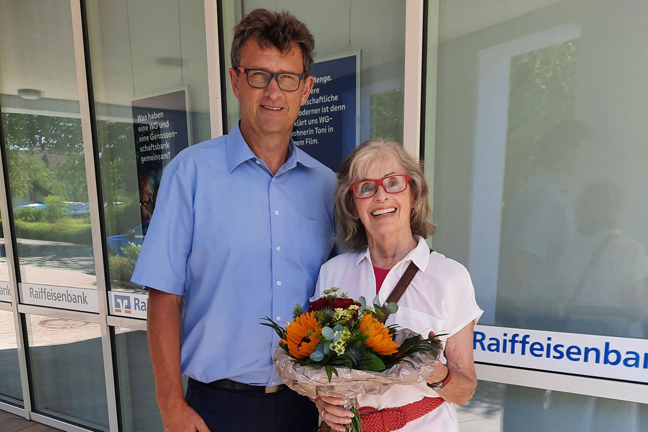 Ein Herr und eine ältere Frau halten einen Blumenstrauß