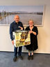 Ein Mann und eine Frau halten eine verpackte Heißluftfriteuse in der Hand und lächeln