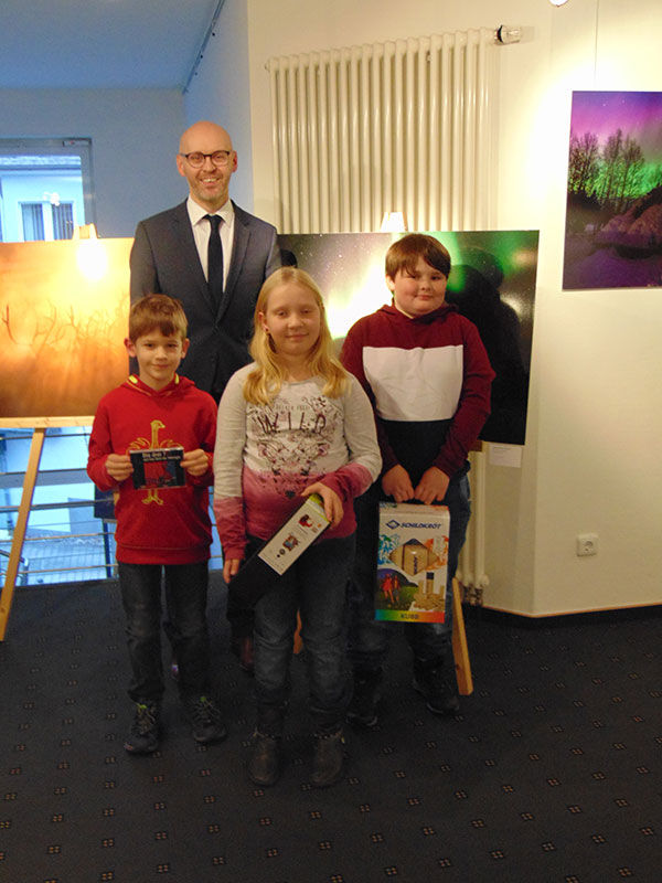 Ein Bankvertreter posiert mit drei Kindern, die Spielzeug erhalten haben
