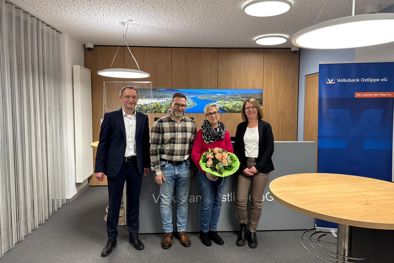 Vier Person, davonhält eine einen Blumenstrauß