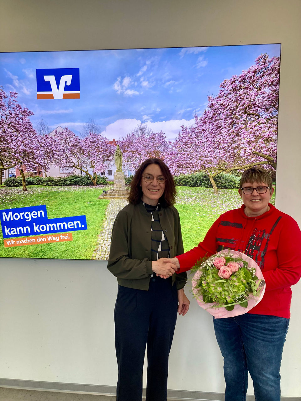 Zwei Frauen stehen nebeneinander - eine hat einen Blumenstrauß in der Hand