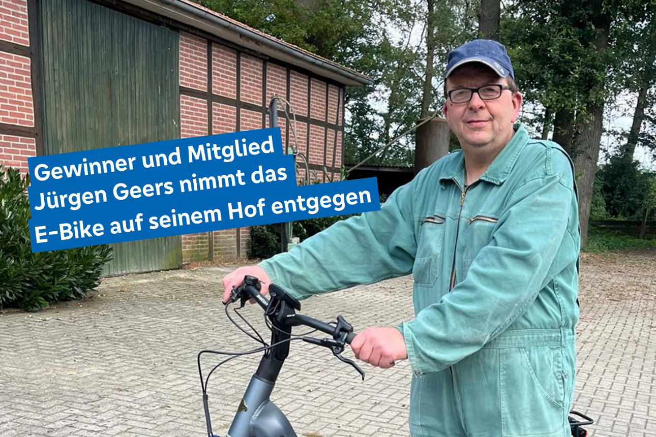 Ein Mann in Latzhose steht neben einem Fahrrad und zeigt eine lässige Szene im Freien. 