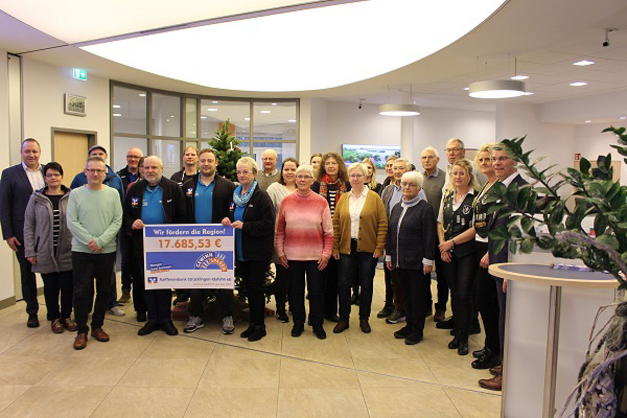 Gruppe mit Scheck in der Schalterhalle