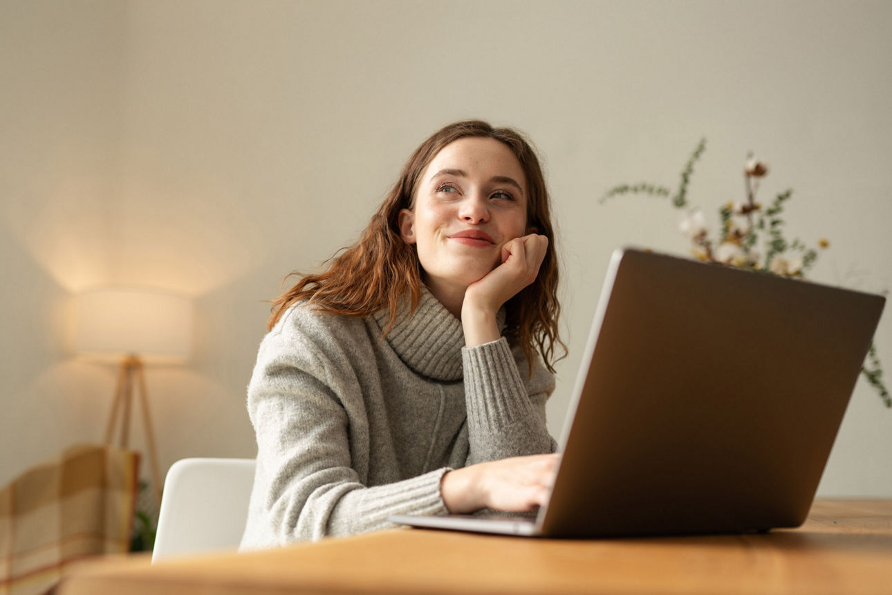 Träumende Frau vor Laptop