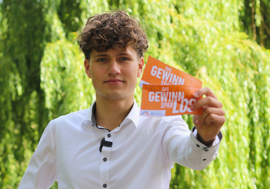 Person zeigt Gewinnsparlose in die Kamera