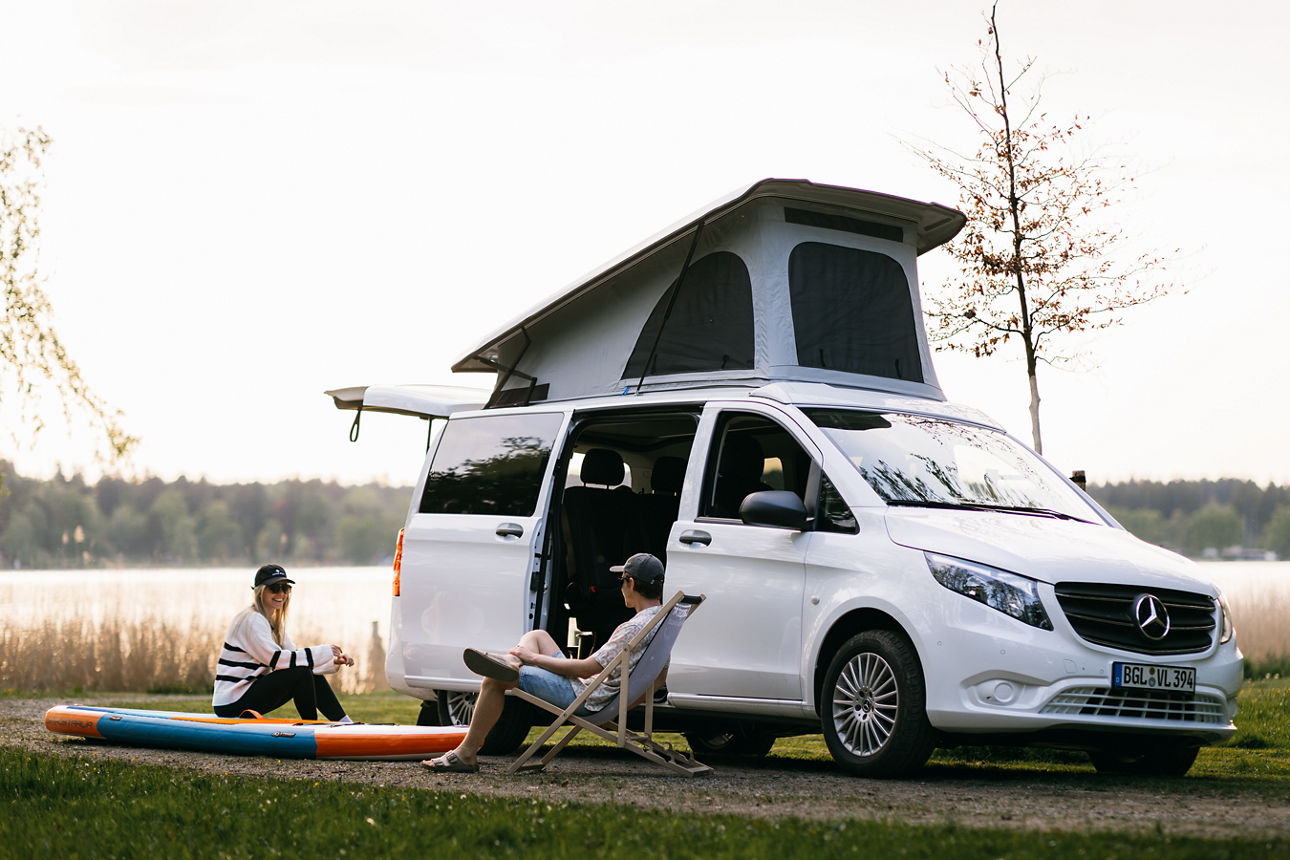 Ein Paar sitzt vor ihrem Camper am See 