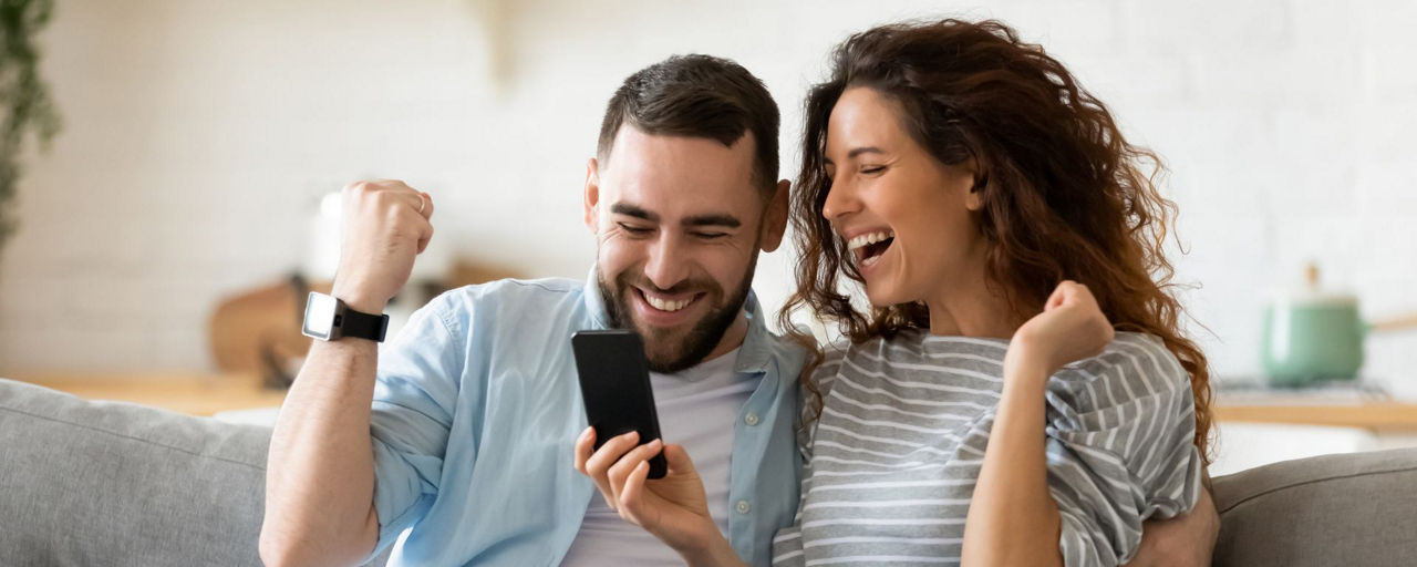 Mann und Frau schauen in ihr Handy und freuen sich