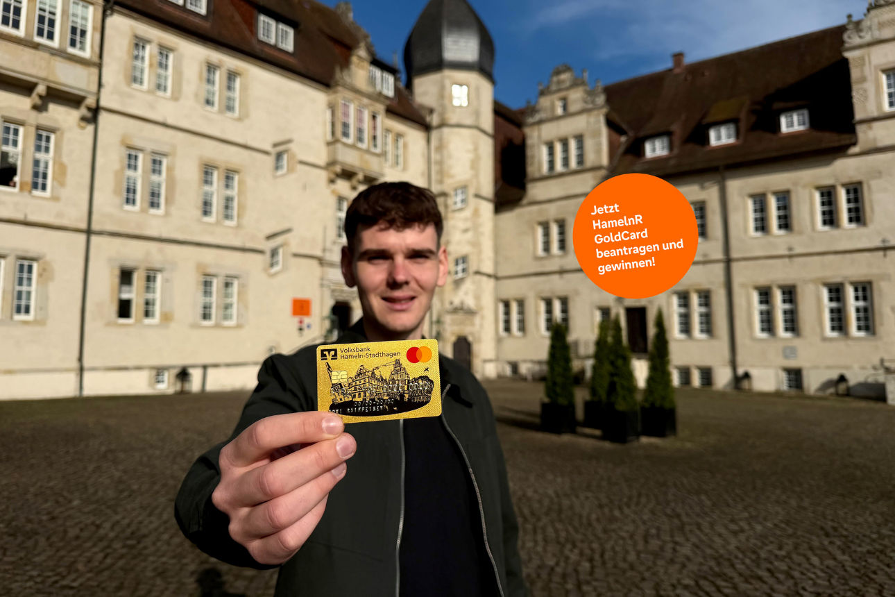 Eine Person hält eine goldene Kreditkarte mit Mastercard-Logo in die Kamera.