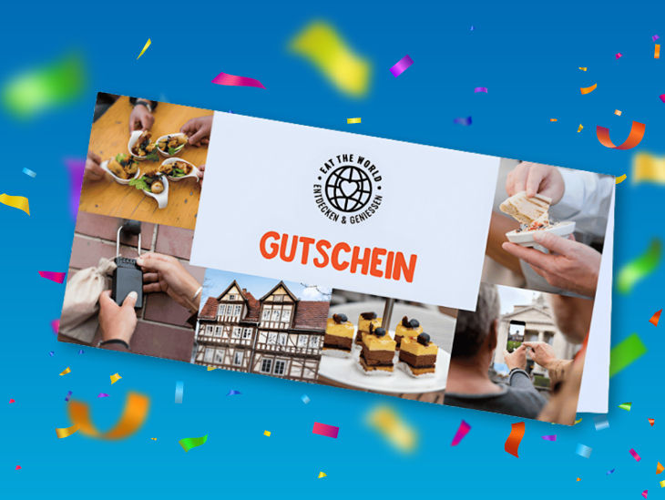 Eine Gutscheinkarte vor blauem Hintergrund mit buntem Konfetti