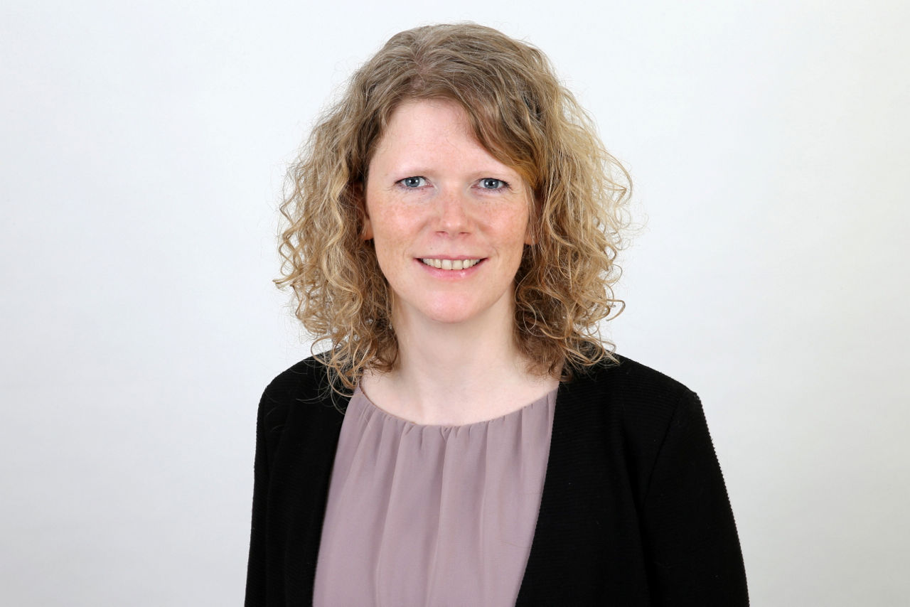 Eine lächelnder Frau schaut in die Kamera.
