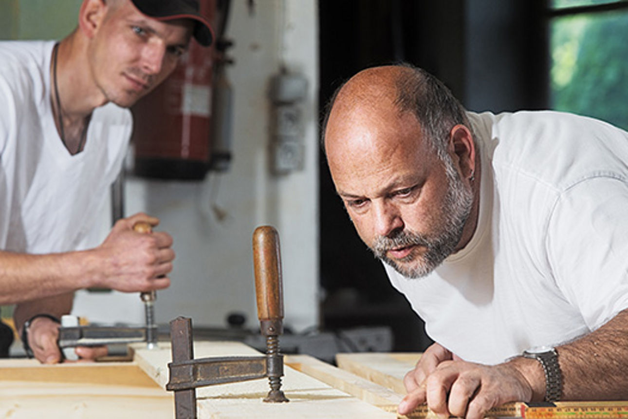 Zwei Männer arbeiten an einem Holzbalken