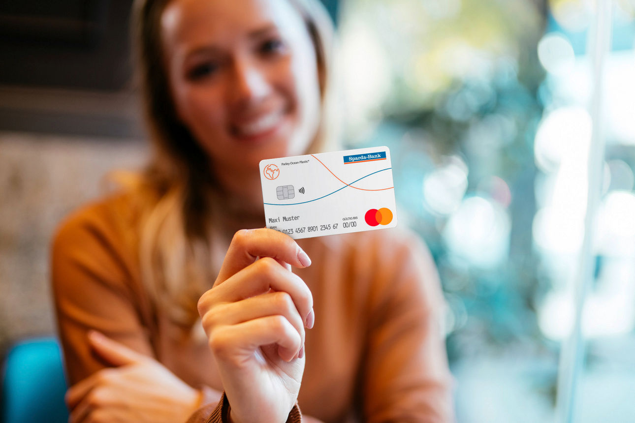 Junge Frau hält girocard Debit Mastercard