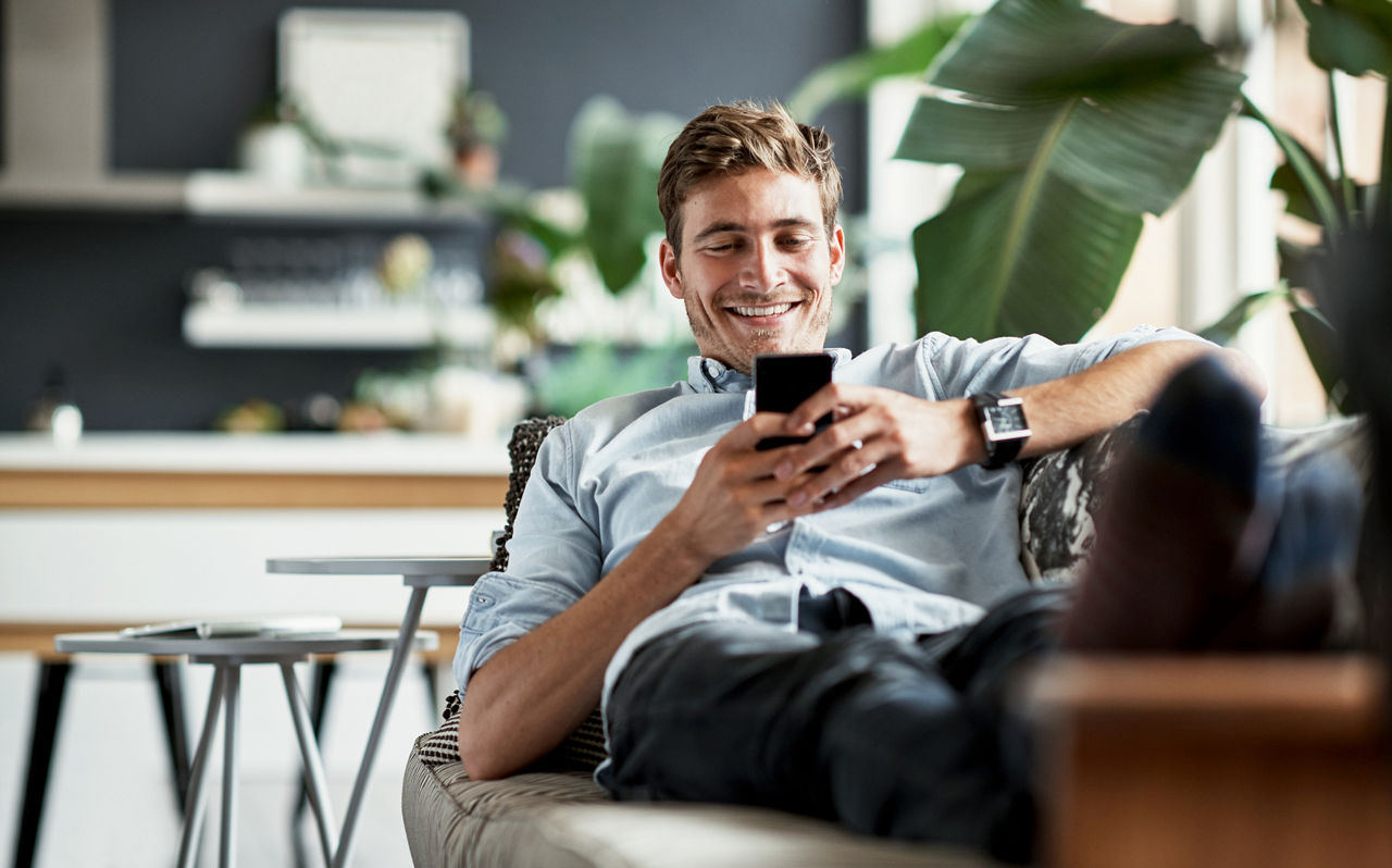 Mann mit einem Smartphone auf einem Sofa