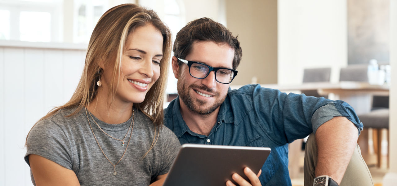 Mann sitzt auf der Couch vor seinem Laptop und prüft seinen Kontostand