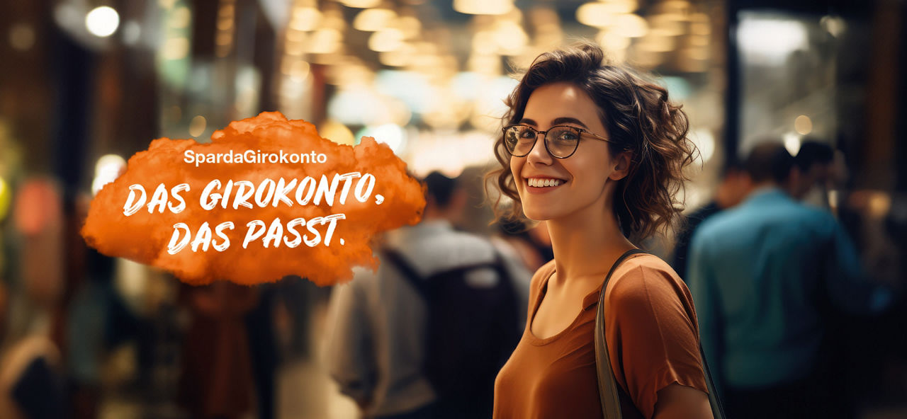 Junge Frau mit Brille steht lächelnd in einer belebten Einkaufshalle. Links im Bild steht auf einer orangenen Fläche "SpardaGirokonto: Das Girokonto, das passt.