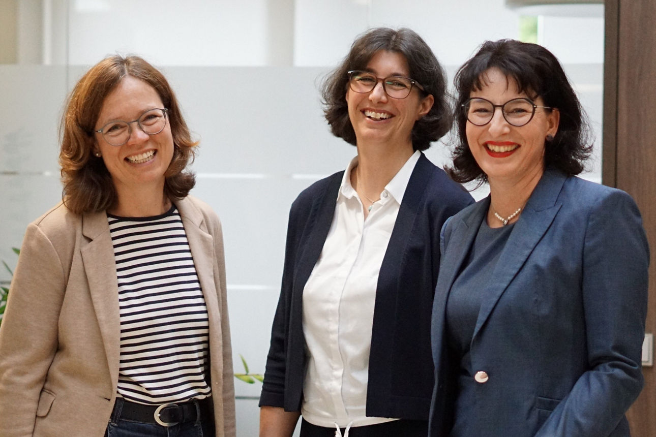 Drei Mitarbeiterinnen schauen lachend in die Kamera