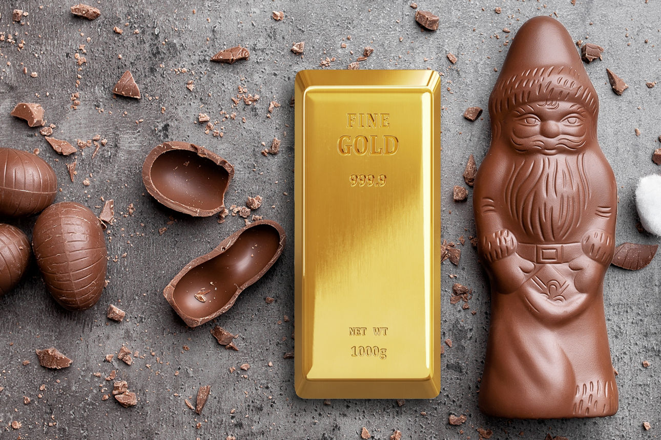 Ein Goldbarren liegt neben einem Schokoladenweihnachtsmann und einer Weihnachtsmann-Mütze