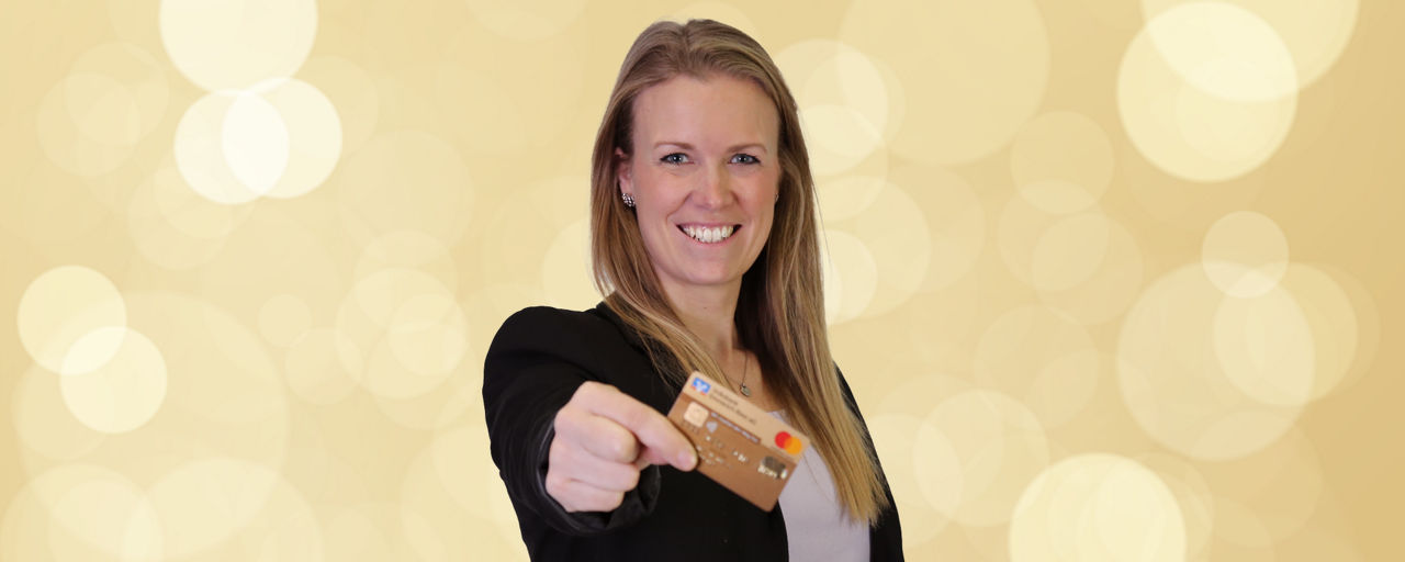 Lächelnde Frau hält goldene Kreditkarte in die Kamera